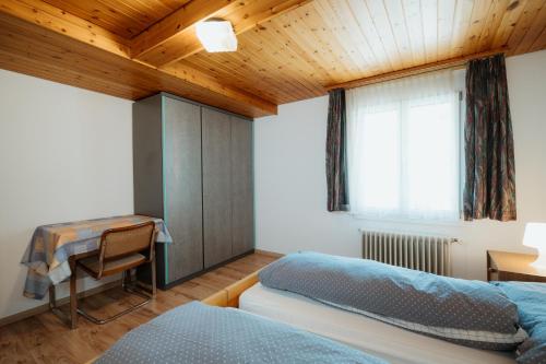 1 dormitorio con 2 camas, escritorio y ventana en Apartment Sonne, en Amden