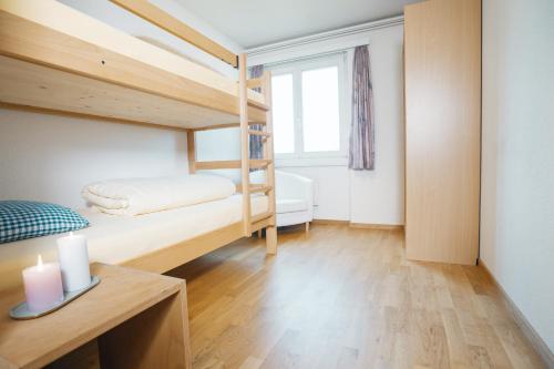a bedroom with two bunk beds and a table with a candle at Schwendihaus Apartment in Amden