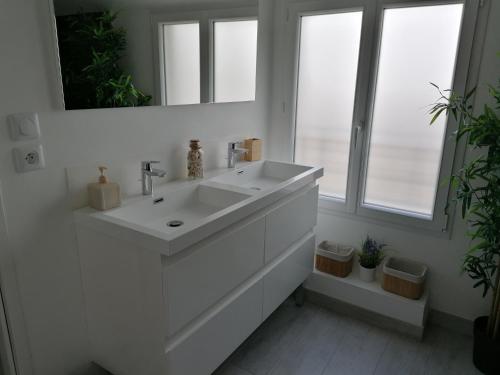 une salle de bain blanche avec un lavabo et un miroir dans l'établissement Maison climatisée 3 chambres au coeur des vignobles bordeaux Léognan, à Léognan