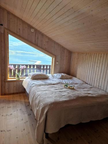 a large bed in a room with a large window at Koselig overnattingssted med fjordutsikt in Sjøvegan