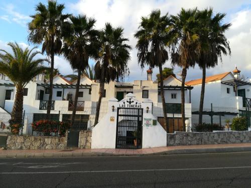 ein weißes Gebäude mit einem Tor und Palmen in der Unterkunft Apartment Laura in Puerto Rico with ocean view free WiFi and Nespresso coffee in Puerto Rico de Gran Canaria