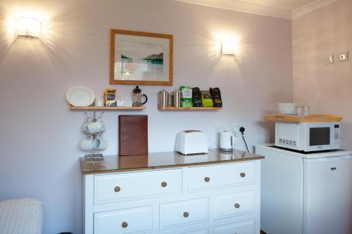 a kitchen with a white dresser with a microwave at Taigh Toilichte in Fort William