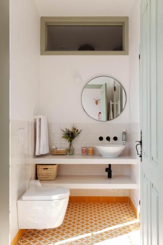 a bathroom with a sink and a toilet and a mirror at Casa Mondina Townhouse in Alcácer do Sal
