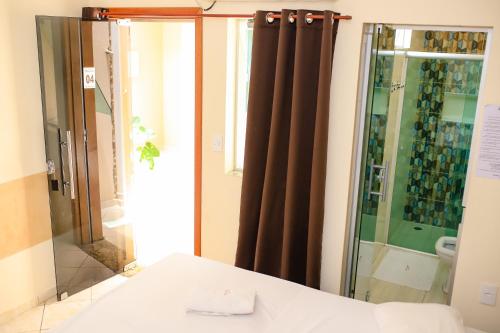 een badkamer met een douche en een glazen deur bij Pousada Santa Cruz in Aparecida