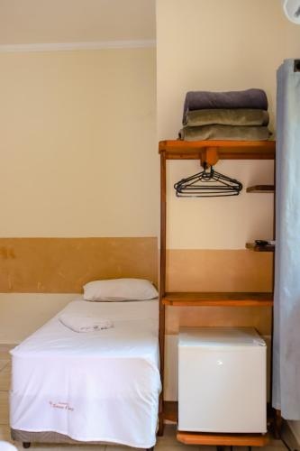 a small room with a bed and a shelf at Pousada Santa Cruz in Aparecida