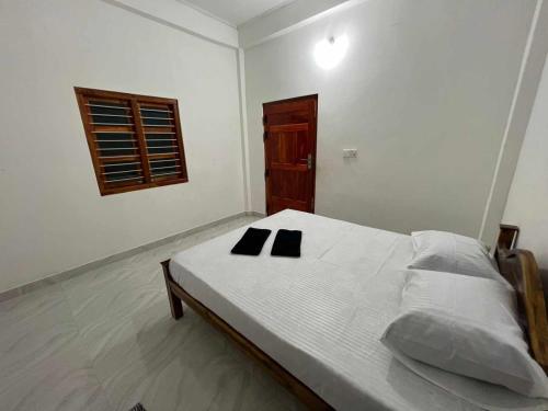 a white bedroom with a bed with two black pillows on it at 'Villa'chava in Chavakachcheri