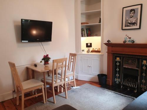 a living room with a table and chairs and a television at Willow House Excellent accomodation Central Exeter-Uni-Chiefs-RD&E-Courtyard Garden-Parking-Sleeps up to 6 in Exeter