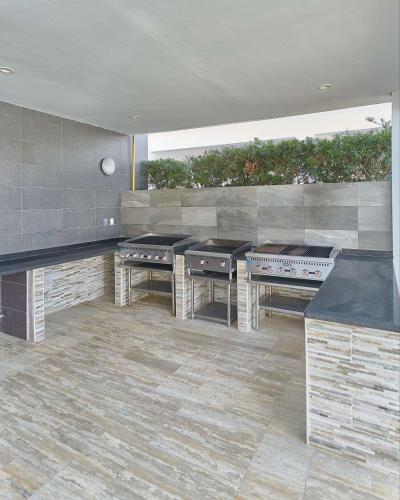 a large kitchen with three tables and a grill at Elegante Aqua Marine Apartamento Juan Dolio in Juan Dolio