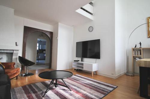a living room with a flat screen tv and a table at Le grand bassin 10 min Disney 25 min Paris 11guests in Lognes