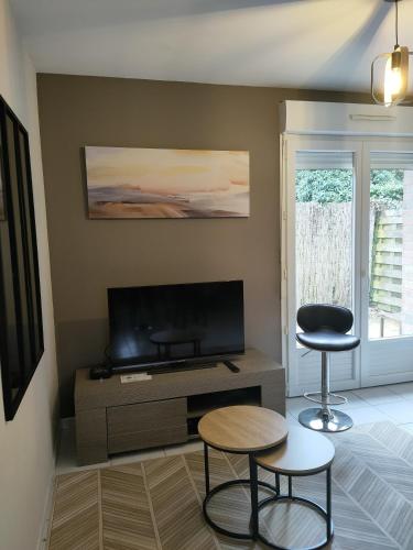 a living room with two stools and a flat screen tv at Tresor de Beaurains in Beaurains