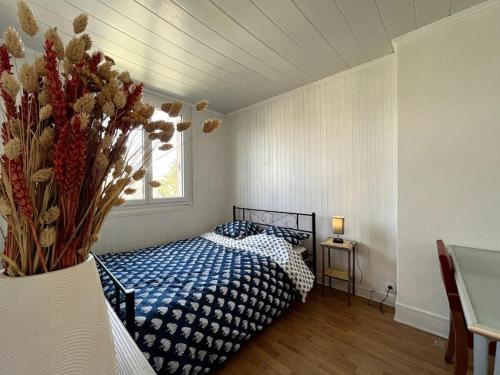 ein Schlafzimmer mit einem Bett und einer Vase aus Blumen in der Unterkunft Le Panorama d'Avon - 10' Gare in Avon