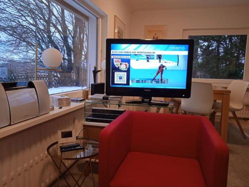 een woonkamer met een rode bank en een televisie bij Hexenstube Jorjina - WLAN - Garten- tolles Bad -Wandern -Mountainbike - Motorradurlaub in Braunlage