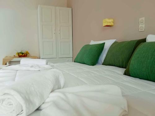 a large white bed with green pillows and a door at Lunzi Verde in Laganas
