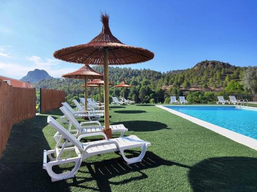a group of chairs and umbrellas next to a pool at Casa Rural Puente del S,egura G in Elche de la Sierra