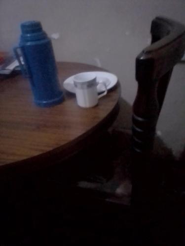 ein Holztisch mit einer Flasche und einer Tasse darauf in der Unterkunft Pilgrims home in Kampala