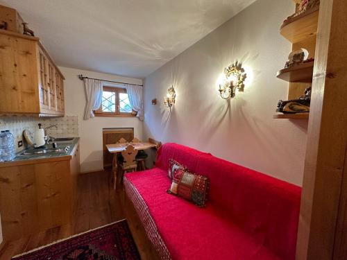 a living room with a red couch in a kitchen at Pecol Cozy Apartment R&R in Cortina dʼAmpezzo