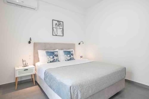 a white bedroom with a large bed and a side table at Cozy apartment in a new building apartment 2 in Piraeus