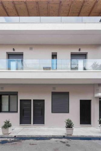 a white building with black windows and a balcony at Cozy apartment in a new building apartment 2 in Piraeus