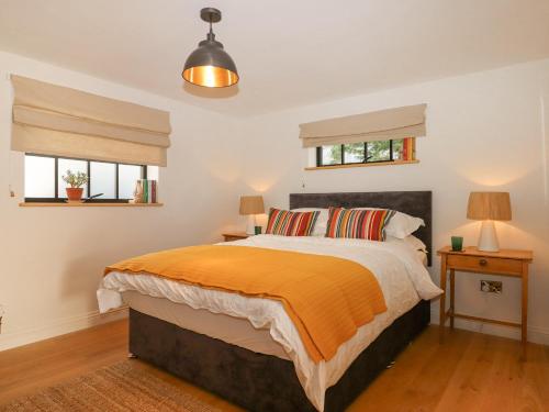 a bedroom with a bed with an orange comforter and two windows at Church Farm Dairy in Exeter