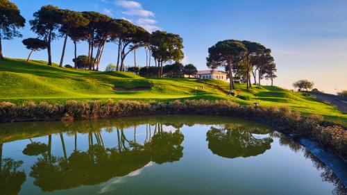 a golf course with a pond in the foreground at Casa Velha do Palheiro Relais & Chateaux in Funchal