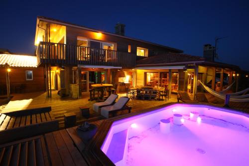 une piscine devant une maison la nuit dans l'établissement Villa Lodge Natureo, à Seignosse