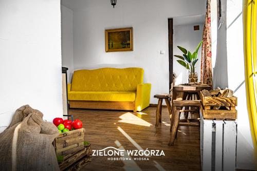 プシビツにあるZielone Wzgórza - Hobbitowe Domki na Kaszubachのリビングルーム(黄色のソファ、テーブル付)