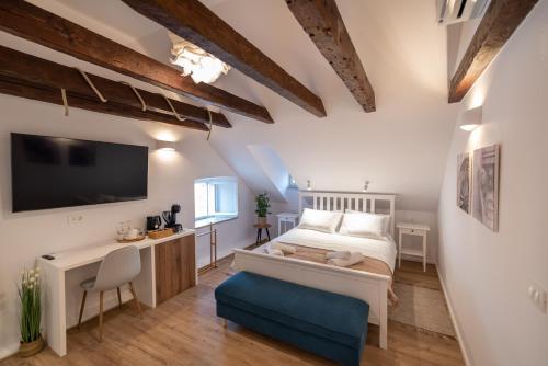 una camera da letto con un letto, una scrivania e una TV di Shee-Lu Suite 2 a Dubrovnik