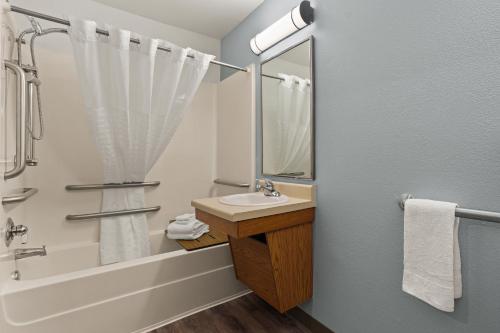a bathroom with a sink and a tub and a mirror at WoodSpring Suites Macon West I-475 in Macon