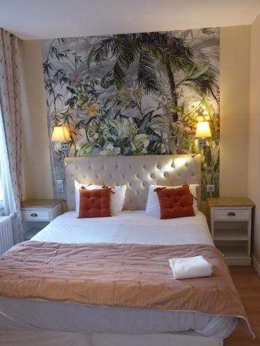 een slaapkamer met een groot wit bed met oranje kussens bij Logis Hôtel Louise de Savoie in Blois