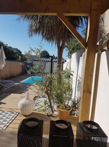 un patio avec une table et des chaises et une piscine dans l'établissement Villa Baliste et sa piscine aux Sables d'Olonne, à Château-dʼOlonne