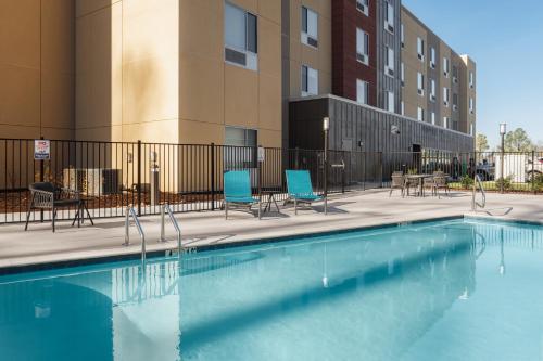 a swimming pool with chairs and tables and a building at TownePlace Suites by Marriott Chattanooga South, East Ridge in Chattanooga