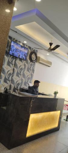 Ein Mann, der in einem Zimmer mit einer Uhr an der Wand sitzt. in der Unterkunft gold stays hotel near IGI international airport in Neu-Delhi
