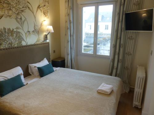 a bedroom with a bed with blue pillows and a window at Logis Hôtel Louise de Savoie in Blois