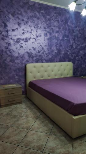 een bed in een kamer met een paarse muur bij Casa Amici Miei in Catania