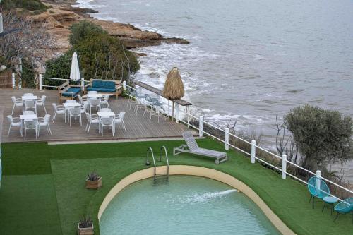 a swimming pool with chairs and tables and the ocean at Bahía de Montecarlo in Alcanar