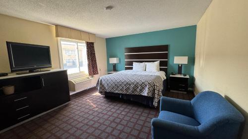 a hotel room with a bed and a chair and a television at Americas Best Value Inn New London Mystic in New London