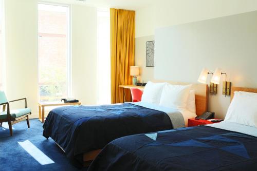 a hotel room with two beds and a chair at The Durham Hotel in Durham