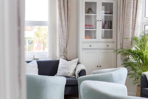 a living room with a blue couch and white chairs at Poole Park House in Poole