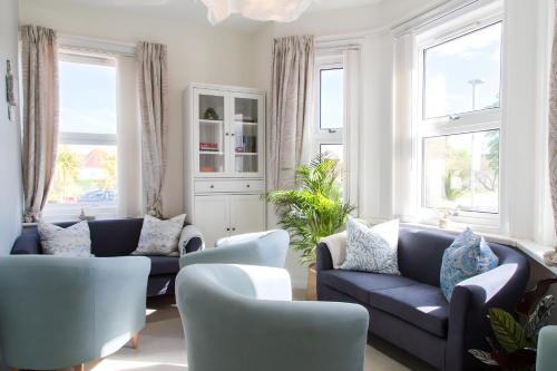a living room with two blue couches and windows at Poole Park House in Poole