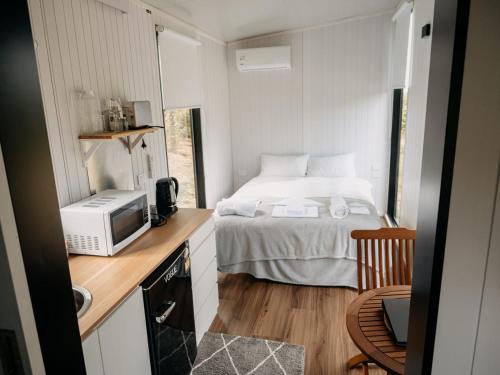 a small bedroom with a bed and a microwave at Bronte Tiny House in Mahana