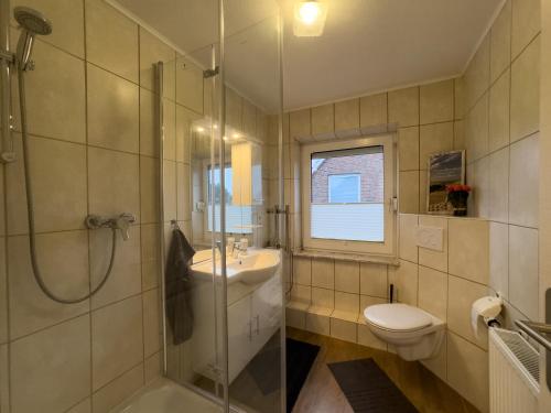 a bathroom with a shower and a sink and a toilet at Windfang 1 in Hooksiel in Wangerland