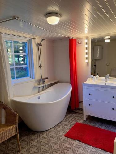 baño con bañera blanca grande y lavamanos en Stuga i Östhammar, en Östhammar