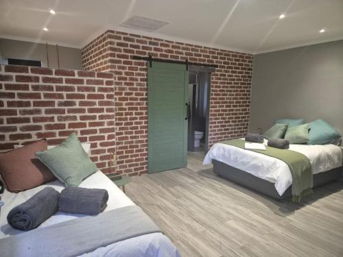 a bedroom with two beds and a brick wall at @241 Enkeldoorn Guesthouse in Pretoria