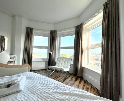 Un dormitorio con una cama y una silla y ventanas. en The Haven, en Ventnor