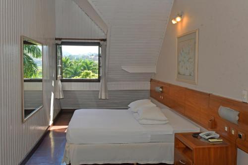a small bedroom with a bed and a window at Hotel Amoreiras in Extrema