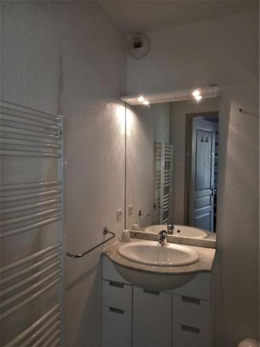 une salle de bain blanche avec un lavabo et un miroir dans l'établissement Maison de vacances Aubignan, à Aubignan