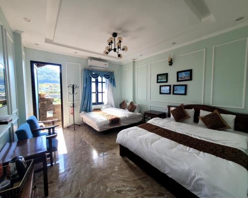 Habitación de hotel con 2 camas, mesa y sillas en NHÀ NGHỈ-HOMESTAY -KHÁCH SẠN ĐỒNG VĂN Hà Giang, en Dồng Văn