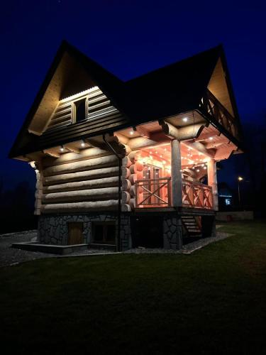 a log house with lights on it at night at Chałpy Pod Ostryszem in Ciche