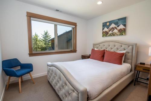 a bedroom with a bed and a window and a blue chair at Suncadia 2 Bdrm Village Chalet Contemporary Cabin in Cle Elum