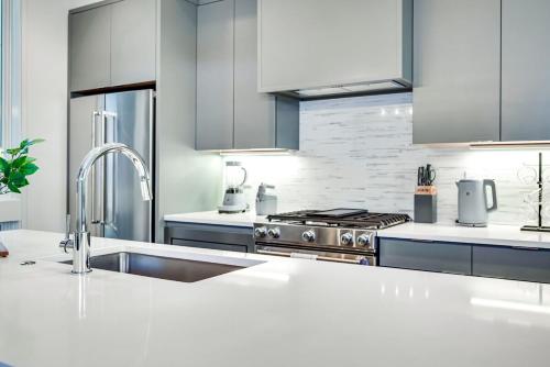 a white kitchen with a sink and a stove at The Duo - 24 Beds & Stunning City Views Rare Find in Nashville